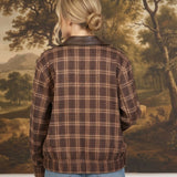 Back view of a woman wearing a graced brown plaid bomber jacket with leather collar accents and blue jeans