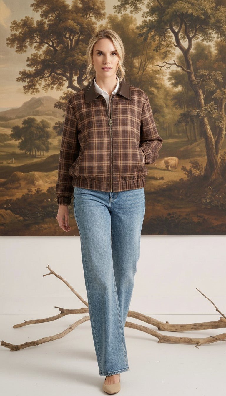 Model wearing a graced brown plaid bomber jacket with leather collar accents and a front zipper, paired with blue jeans