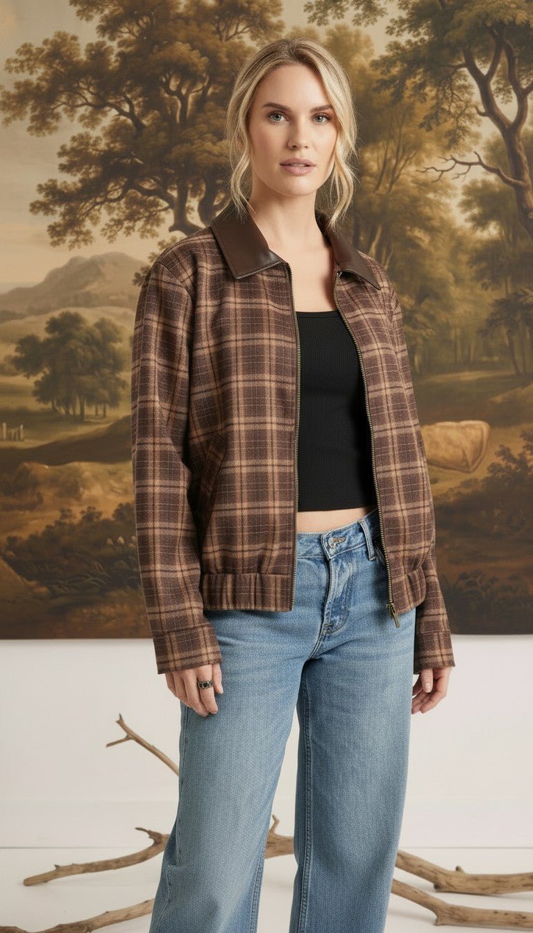 Model wearing a graced brown plaid bomber jacket with leather collar accents over a black top and blue jeans