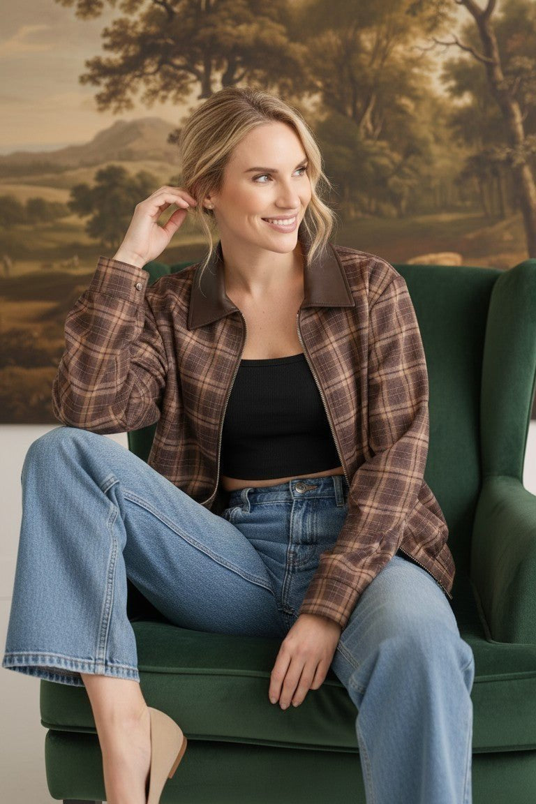 graced Tessa bomber jacket in brown plaid with leather collar, worn by a smiling woman in a green armchair