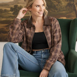 graced Tessa bomber jacket in brown plaid with leather collar, worn by a smiling woman in a green armchair