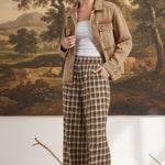 Model wearing graced Tina plaid checker pants with a brown denim jacket and platform sandals in a studio setting.