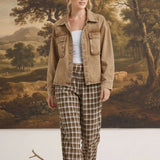 Model wearing graced The Tina Plaid Checker Pants in brown and white with a tan denim jacket in a studio setting.
