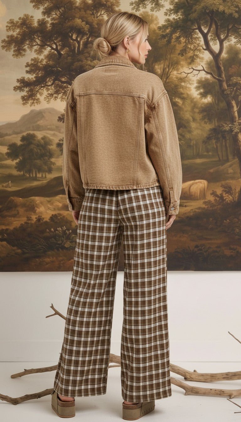 Model wearing graced Tina plaid checker pants in brown and white with a tan denim jacket, back view.