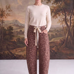 Model wearing graced chocolate-brown barrel pants with a spotted Bambi print, bow-tie waist, and seamed knee detail.