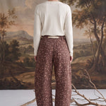Back view of a model wearing graced chocolate-brown barrel pants with a spotted Bambi print and waist bow tie.