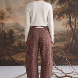 Back view of a model wearing graced chocolate-brown barrel pants with a spotted Bambi print and waist bow tie.